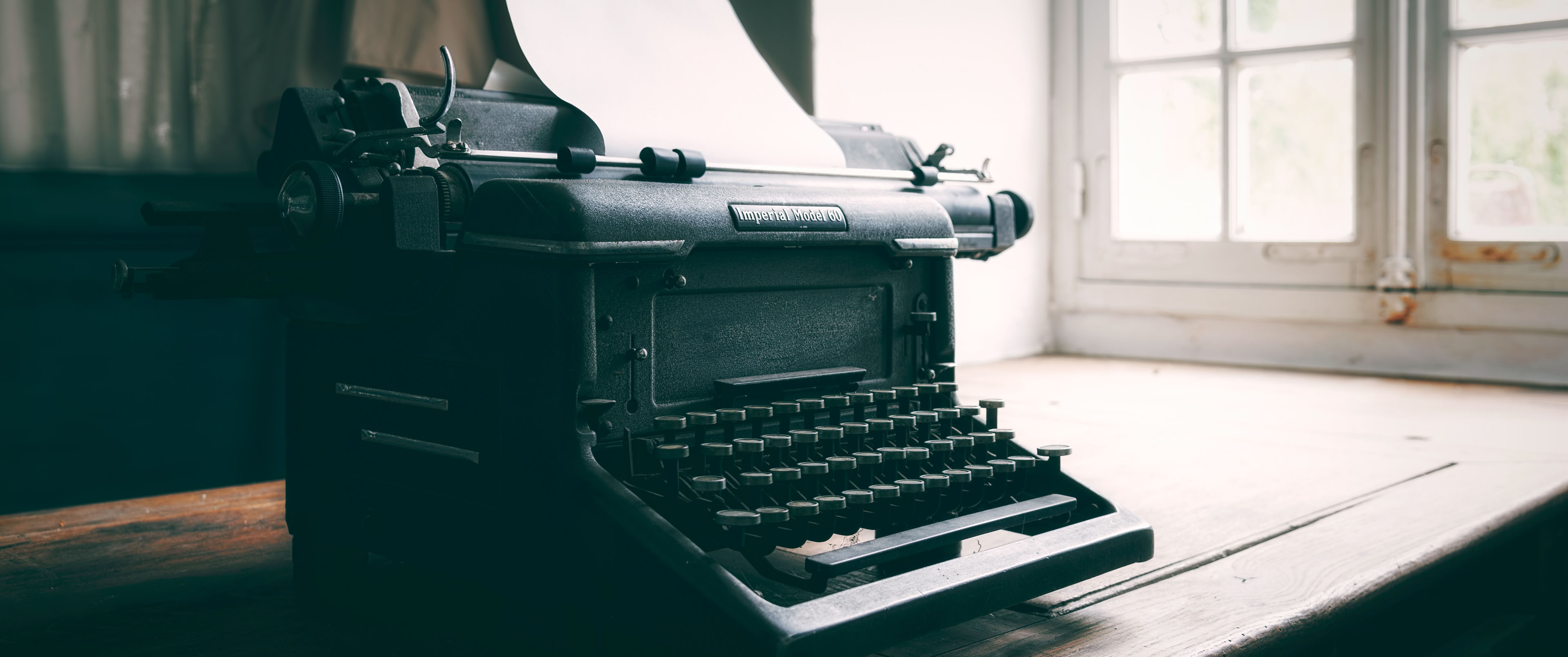 Typewriter on desk, window in background